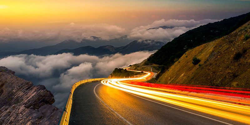 Winding mountain highway at night with light trails symbolizing fast operational modernization