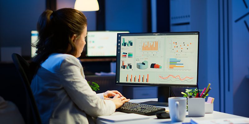 Financial analyst reviewing Power BI dashboards displaying real-time operational and margin analytics in cloud-based data platform